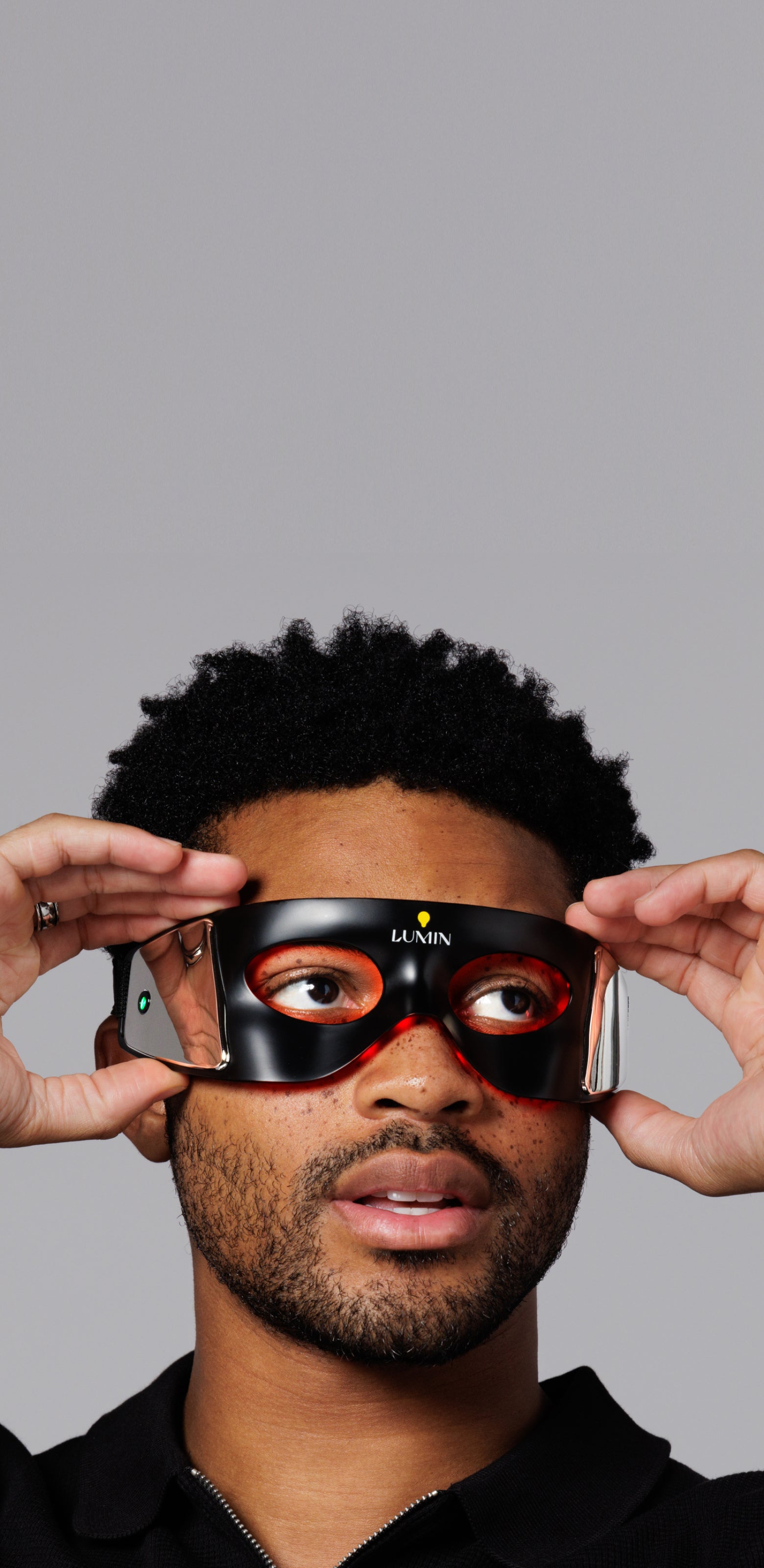 Man wearing futuristic black and orange VR headset on gray background, virtual reality technology, immersive gaming gear