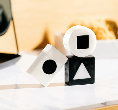 Black and white geometric shaped skincare soap bars on a marble surface.