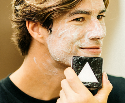 Man applying facial cleanser with a bar soap for skincare.