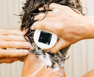 Man washing his hair with a solid shampoo bar.
