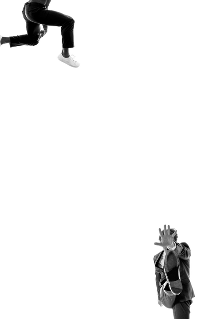 Person in white sneakers and black pants jumping, and person in formal shoe and suit raising hand, black background.