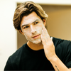 Young man applying white facial cleanser cream on face, skincare routine, men's grooming, clean skin care, bathroom mirror background