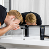 Man washing face at modern bathroom sink with Lumin charcoal face wash tube for daily detox skincare routine.