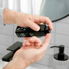 Hands dispensing wrinkle defense serum from black pump bottle in modern bathroom with black faucet and soap dispenser.