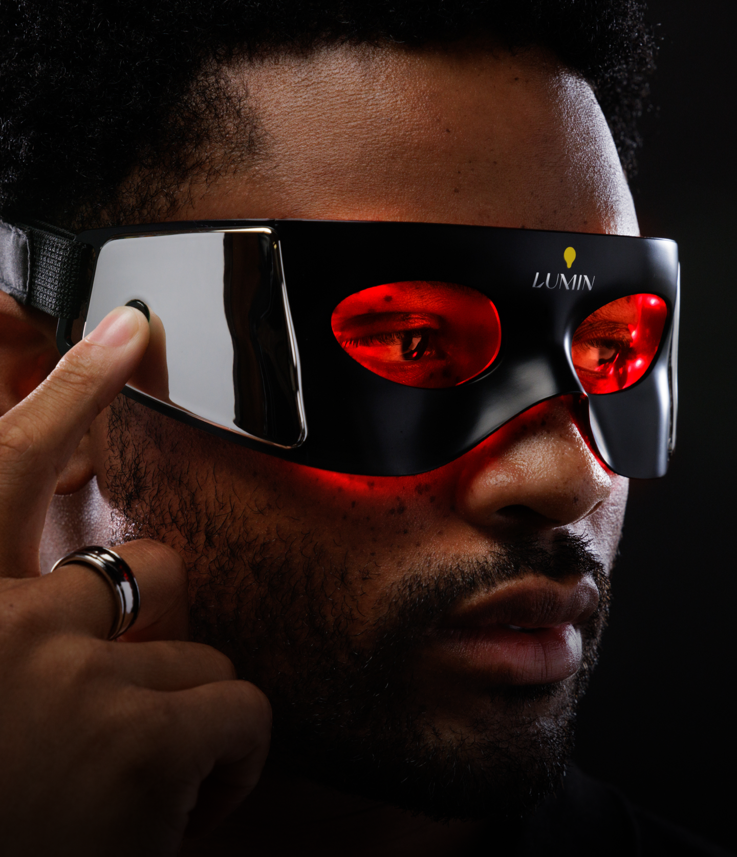 Futuristic black and red VR headset worn by man, featuring sleek design and integrated earphones for immersive virtual reality experience.